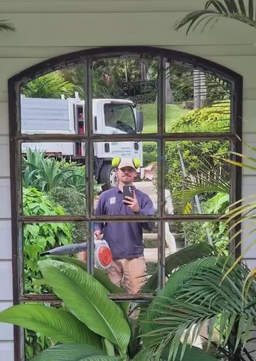 Andoni con equipo de sopladora, reflejo en espejo, camión de trabajo detrás